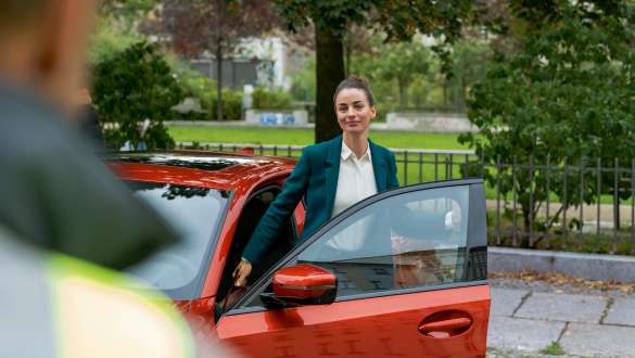 Une femme se trouve devant la porte ouverte de sa BMW.
Une femme se trouve devant la porte ouverte de sa BMW.