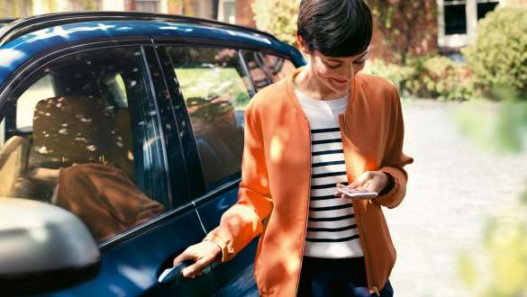 Femme avec vue sur son smartphone Femme descend de la BMW avec vue sur son smartphone.