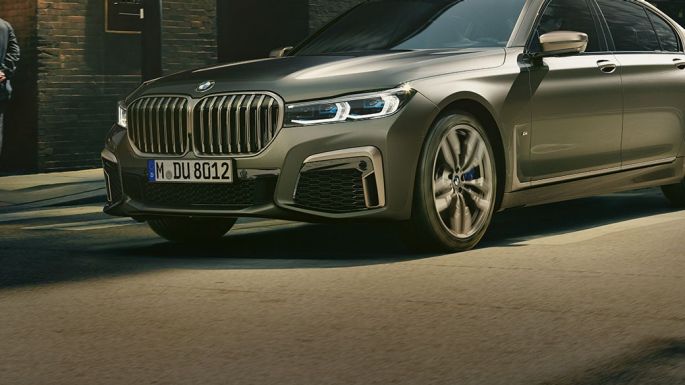 BMW M760Li xDrive dans un décor urbain BMW M760Li xDrive en vue latérale avant, se déplaçant sur une route dans un décor urbain