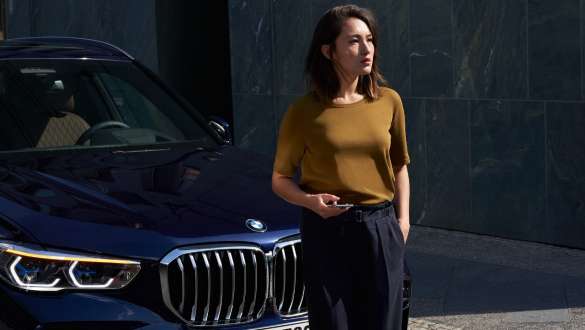 Gestion des pannes et des accidents BMW Gestion des pannes et des accidents BMW Femme avec smartphone devant une BMW