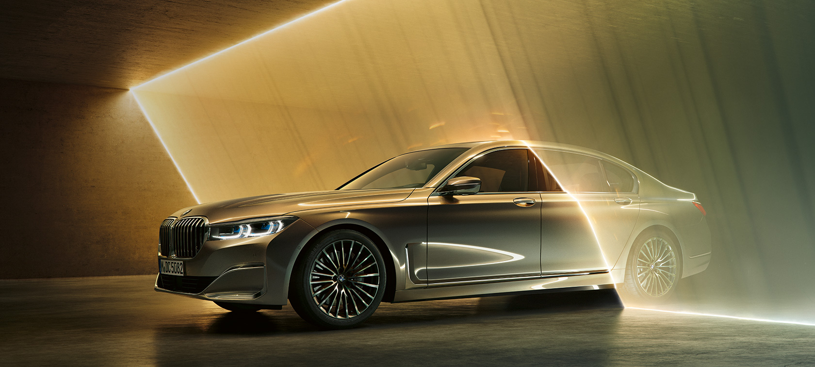 La BMW Série 7 Berline vue de trois quarts avant. BMW Série 7 Berline : vue de trois quarts avant d’une BMW grise entourée de rayons lumineux.
