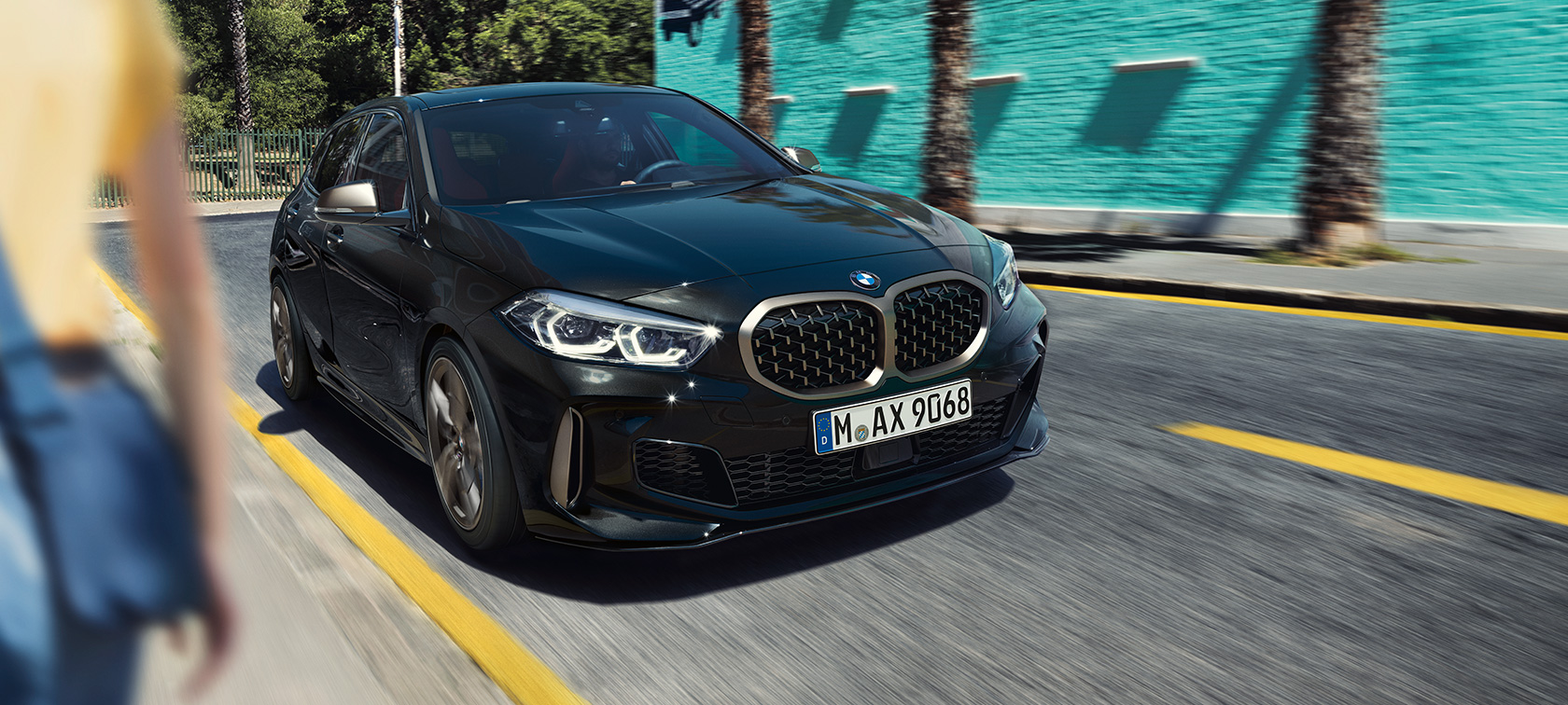 BMW M135i xDrive, vue de trois quarts avant. BMW M135i xDrive en Saphirschwarz metallic, vue de trois quarts avant, en marche.