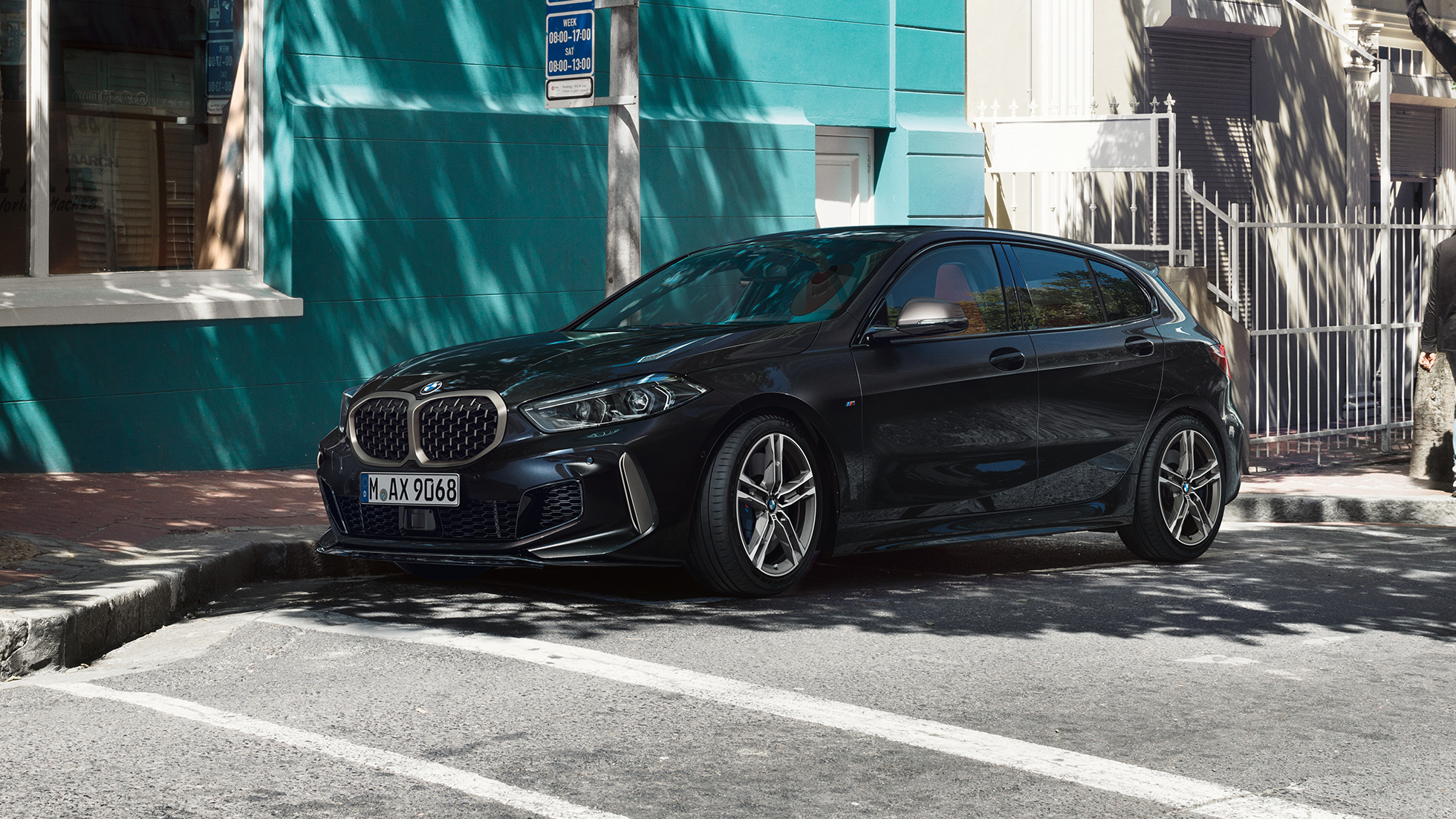 BMW M135i xDrive, vue de trois quarts de profil. BMW M135i xDrive en Saphirschwarz metallic, vue de trois quarts de profil, en stationnement.
