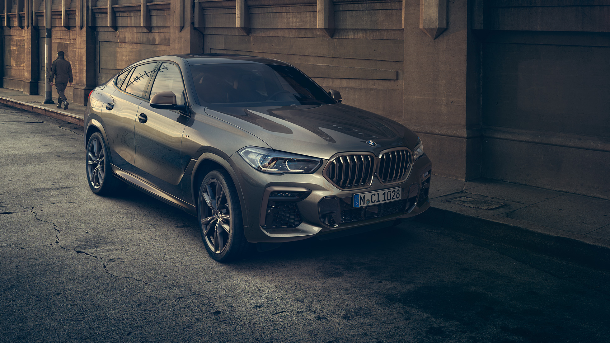 BMW X6 M50i à l’arrêt. La BMW X6 M50i vue de trois quarts avant, à l’arrêt devant un décor urbain.