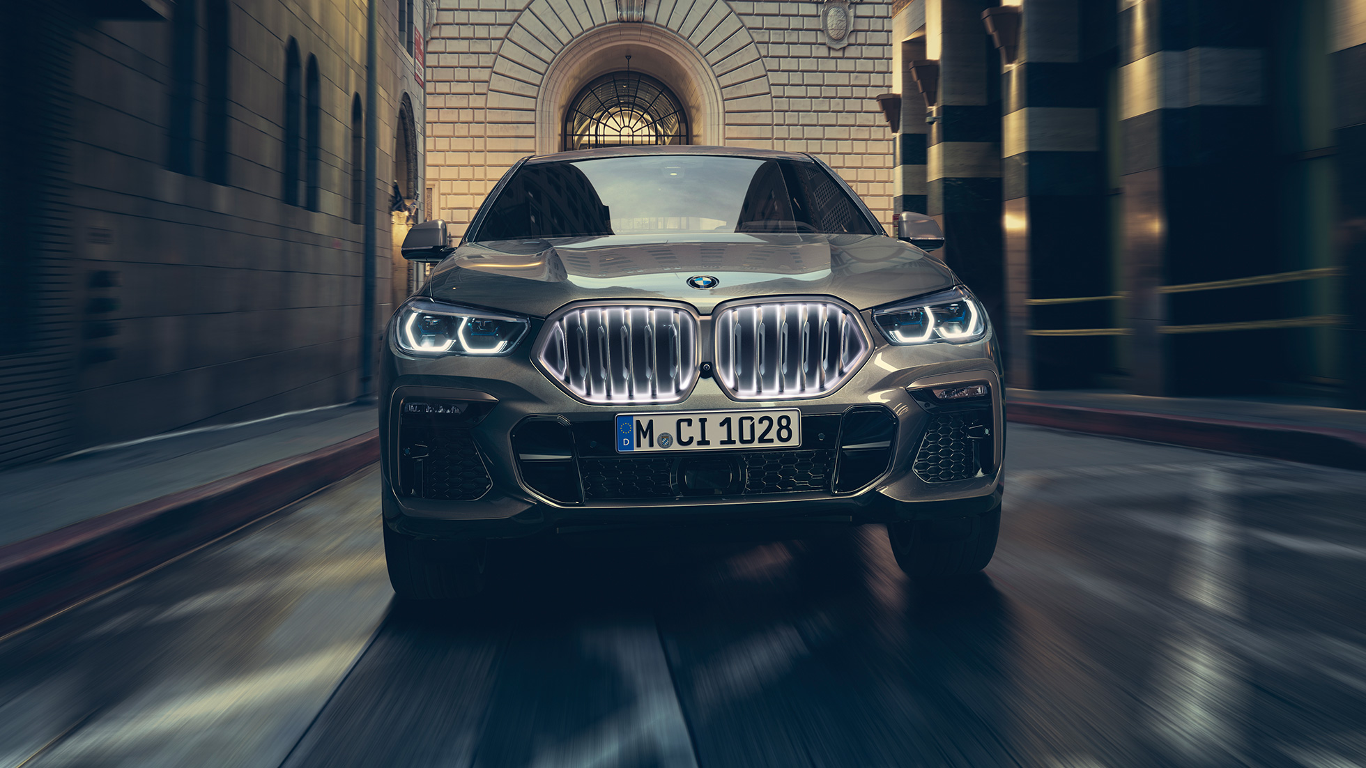 BMW X6 M50i est ses naseaux BMW Iconic Glow. BMW X6 M50i vue de l’avant devant un décor urbain.