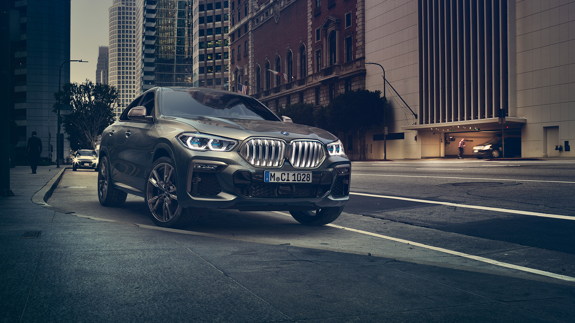 BMW X6 M50i à l’arrêt. La BMW X6 M50i vue de trois quarts avant, à l’arrêt devant un décor urbain.
