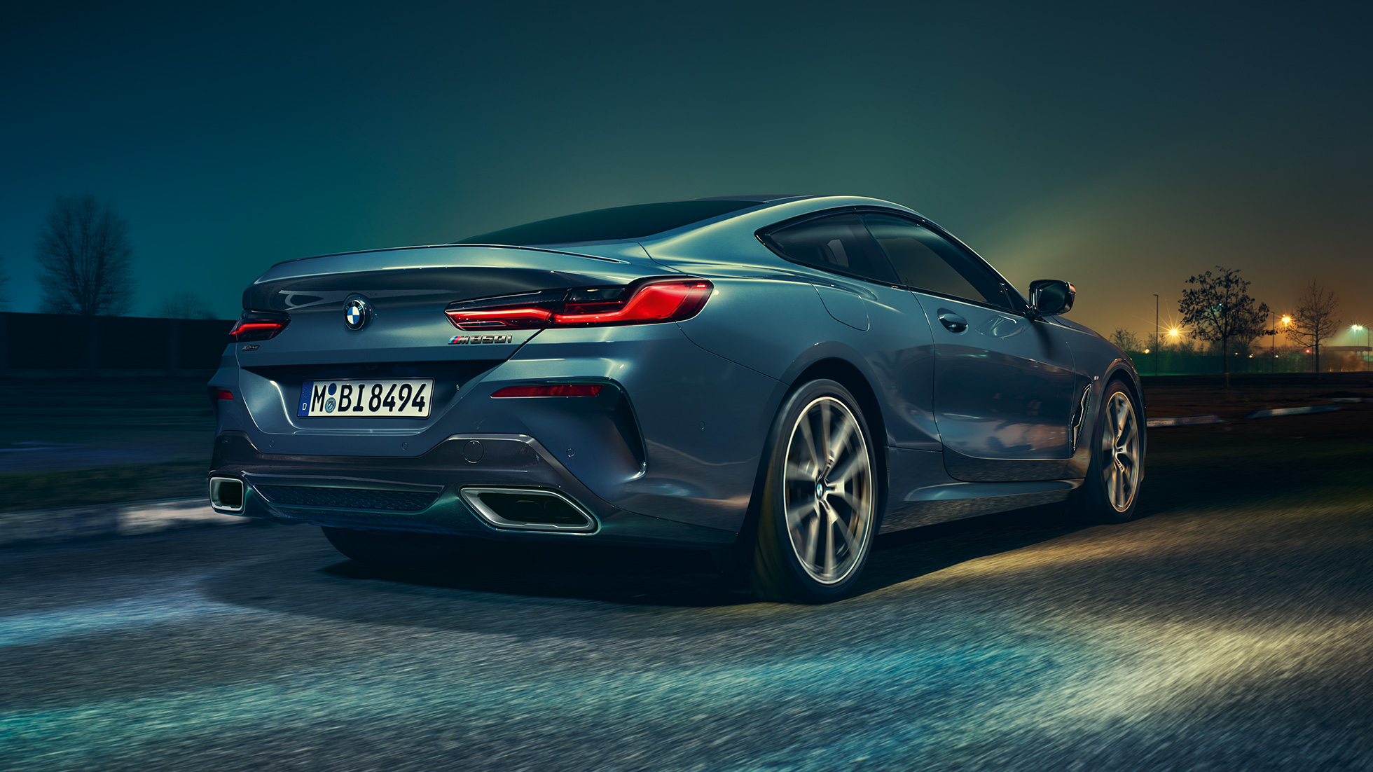 BMW M850i xDrive Coupé, vue arrière. BMW M850i xDrive Coupé en Barcelona Blau metallic en marche, vue nocturne arrière.