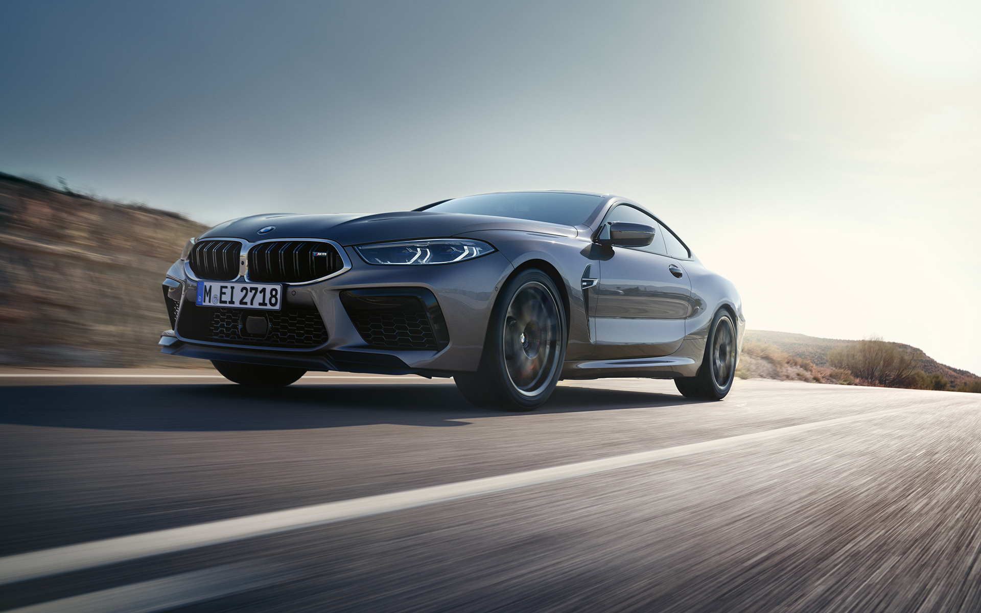 BMW M8 Coupé F92 LCI Facelift 2022 Gratte-ciel gris métallisé vue de trois quarts avant roulant sur une autoroute en contre-plongée