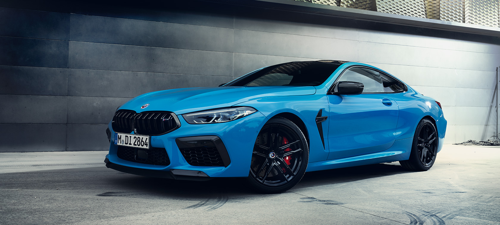 La BMW M8 Competition Coupé F92 LCI restylage 2022 Daytona Beach Blau uni Vue de profil de trois quarts face à un mur