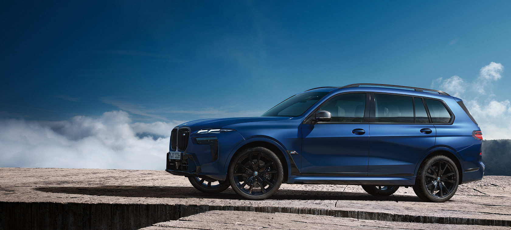 BMW X7 M60i xDrive G07 LCI Frozen Marina Bay Blue vue de profil devant un paysage de montagnes