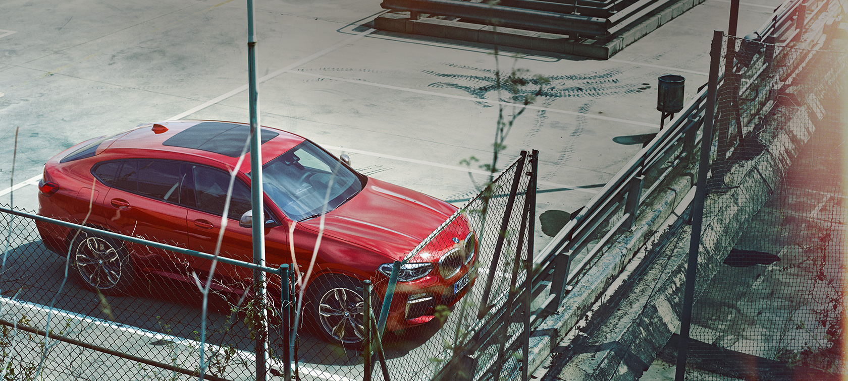BMW X4 en stationnement BMW X4 G02 2018 en Flamencorot Brillanteffekt en stationnement sur un parking couvert, vue en plongée