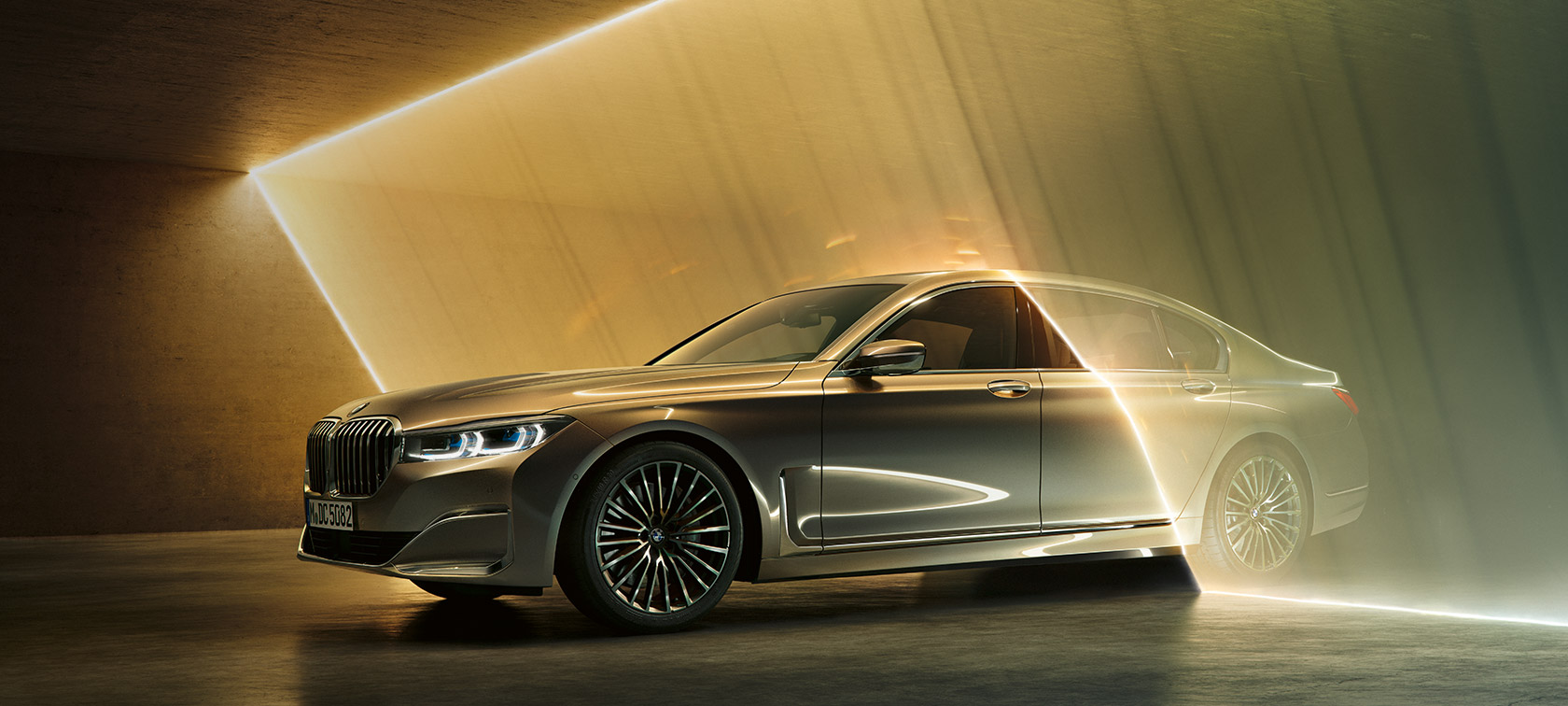 BMW Série 7 Berline : vue de trois quarts avant d’une BMW grise entourée de rayons lumineux.