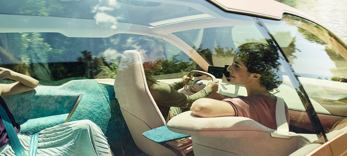 Femme sur le siège passager avant de la BMW Vision iNEXT Femme aux cheveux foncés installée sur le siège du passager avant de la BMW Vision iNEXT, elle se tourne vers l'arrière