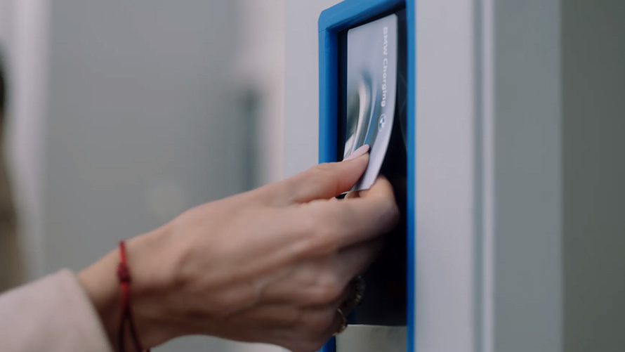 Personne tenant une BMW Charging Card à une station de recharge publique Personne tenant une BMW Charging Card à une station de recharge publique