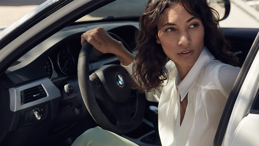 BMW Value Service La cliente du service BMW regarde par la porte ouverte de sa BMW