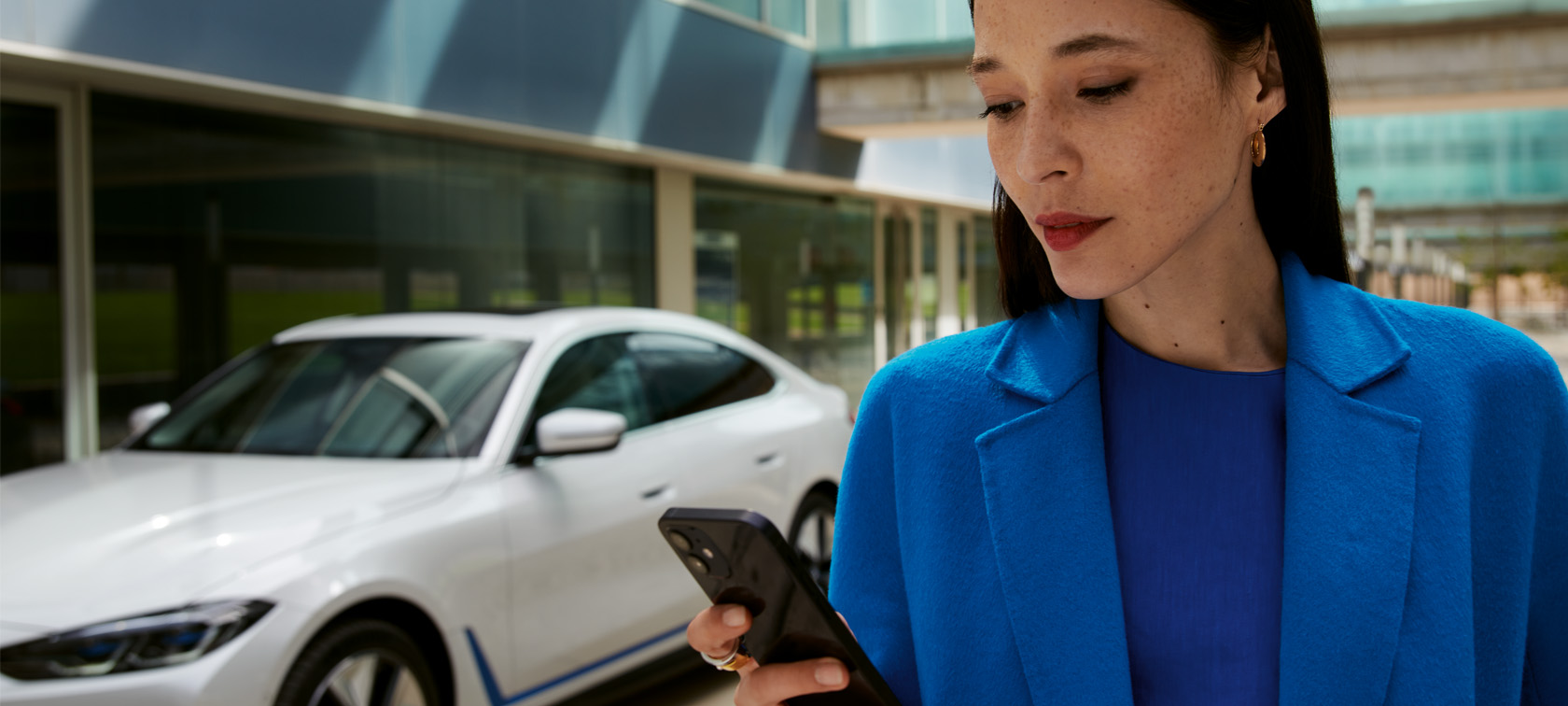 Femme devant la BWW i4 qui utilise son smartphone